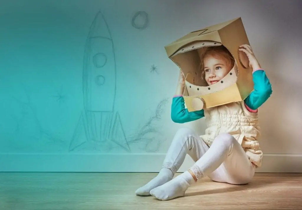Creative child playing with a cardboard astronaut helmet in a colorful space-themed room.
